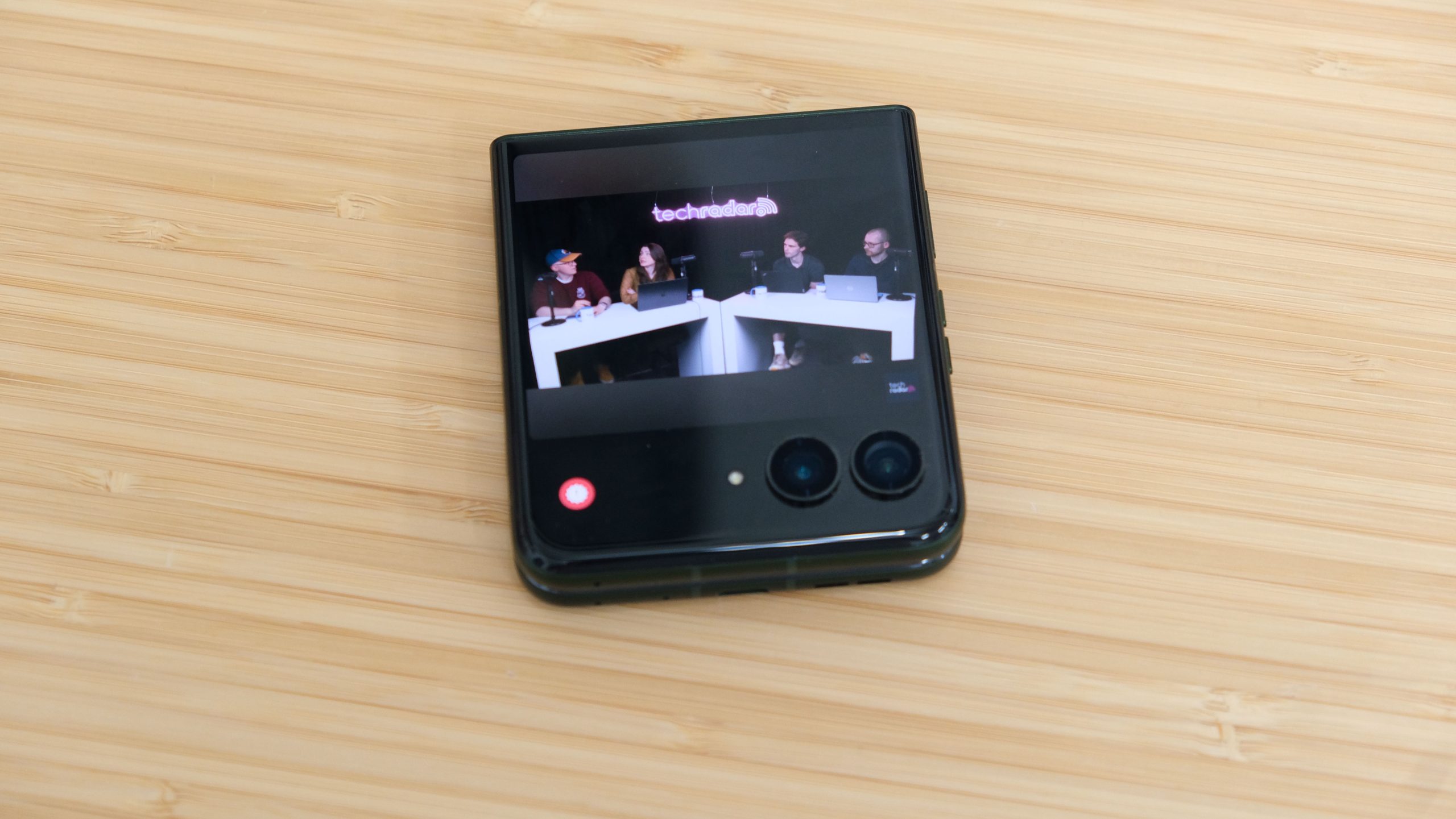 The Motorola Razr Plus 2026 in the hand and on a wooden table