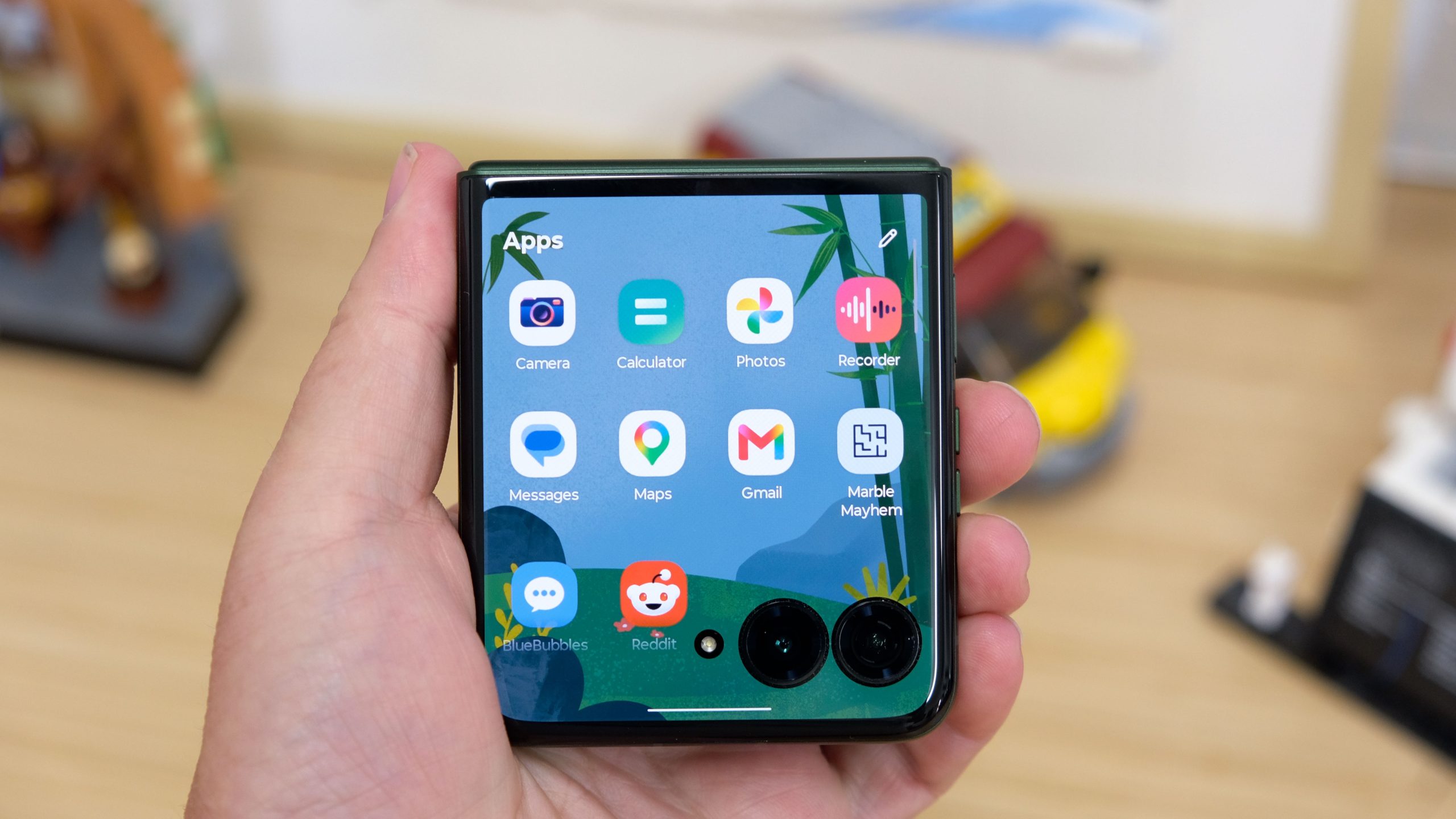 The Motorola Razr Plus 2026 in the hand and on a wooden table