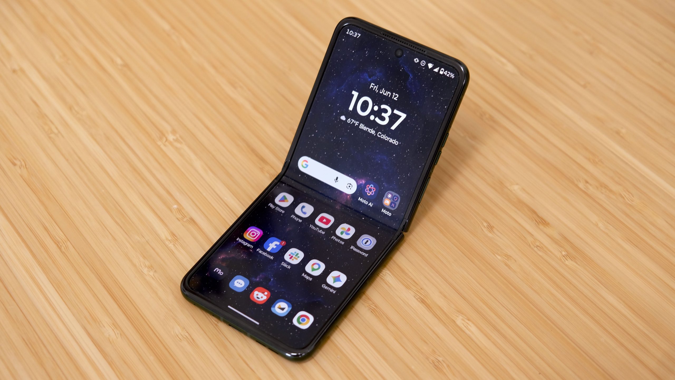 The Motorola Razr Plus 2026 in the hand and on a wooden table