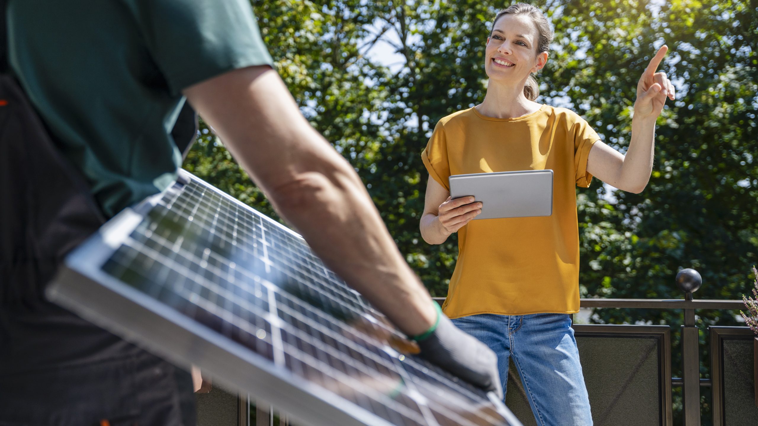 Woman directing worker holding solar panel