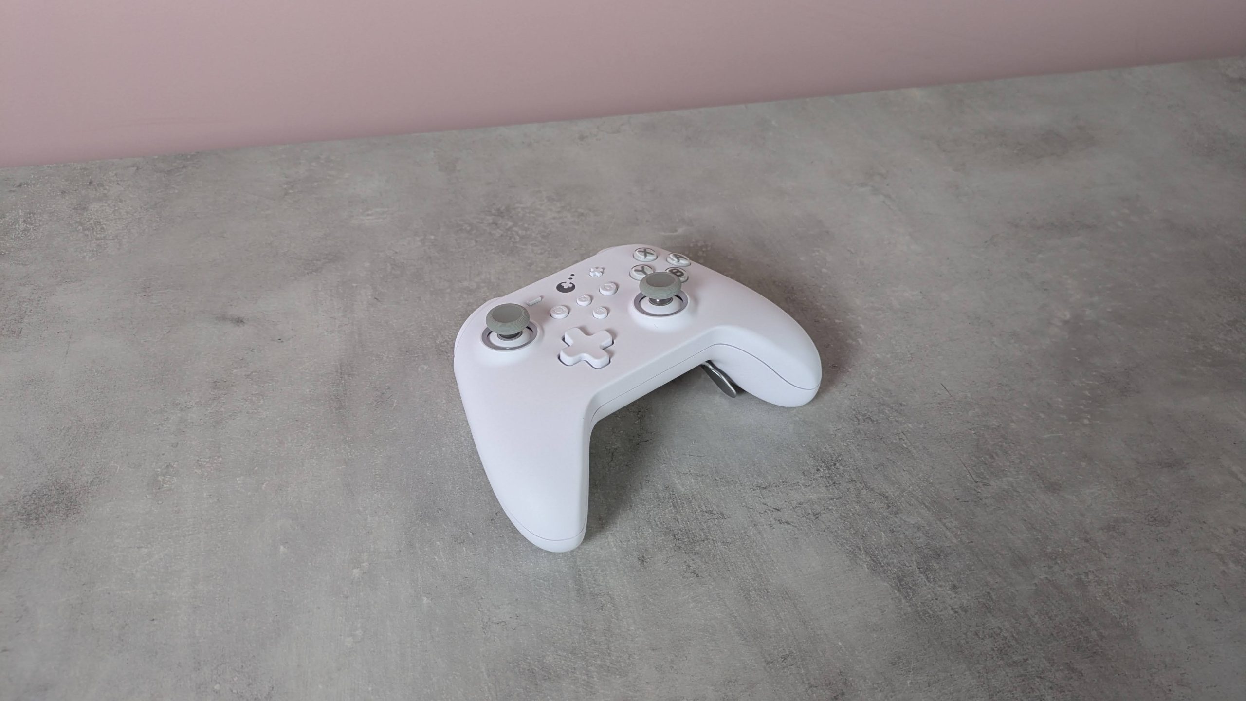 Three-quarter view of GuliKit KK3 Max, on a desk with pink wall in background
