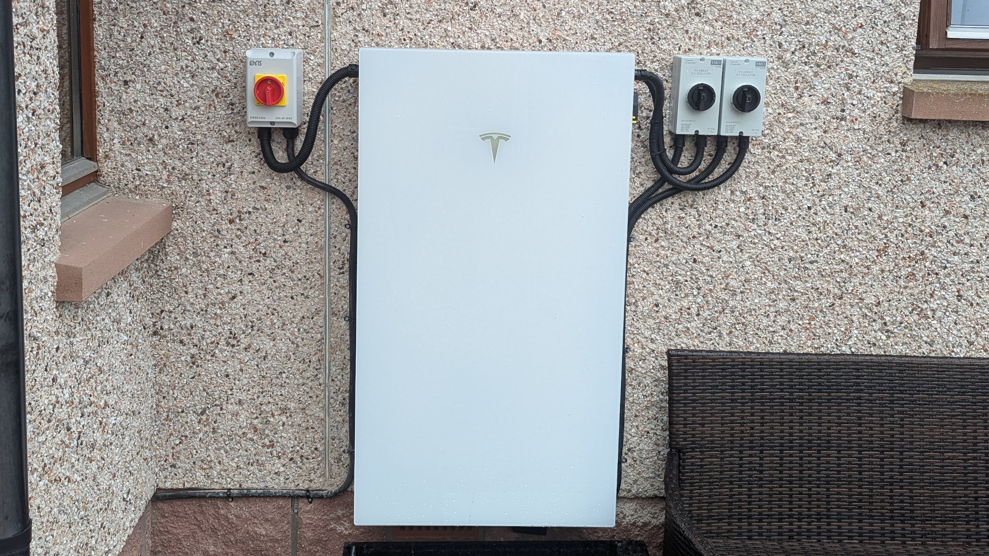 Tesla Powerwall battery mounted on the outside wall of a house
