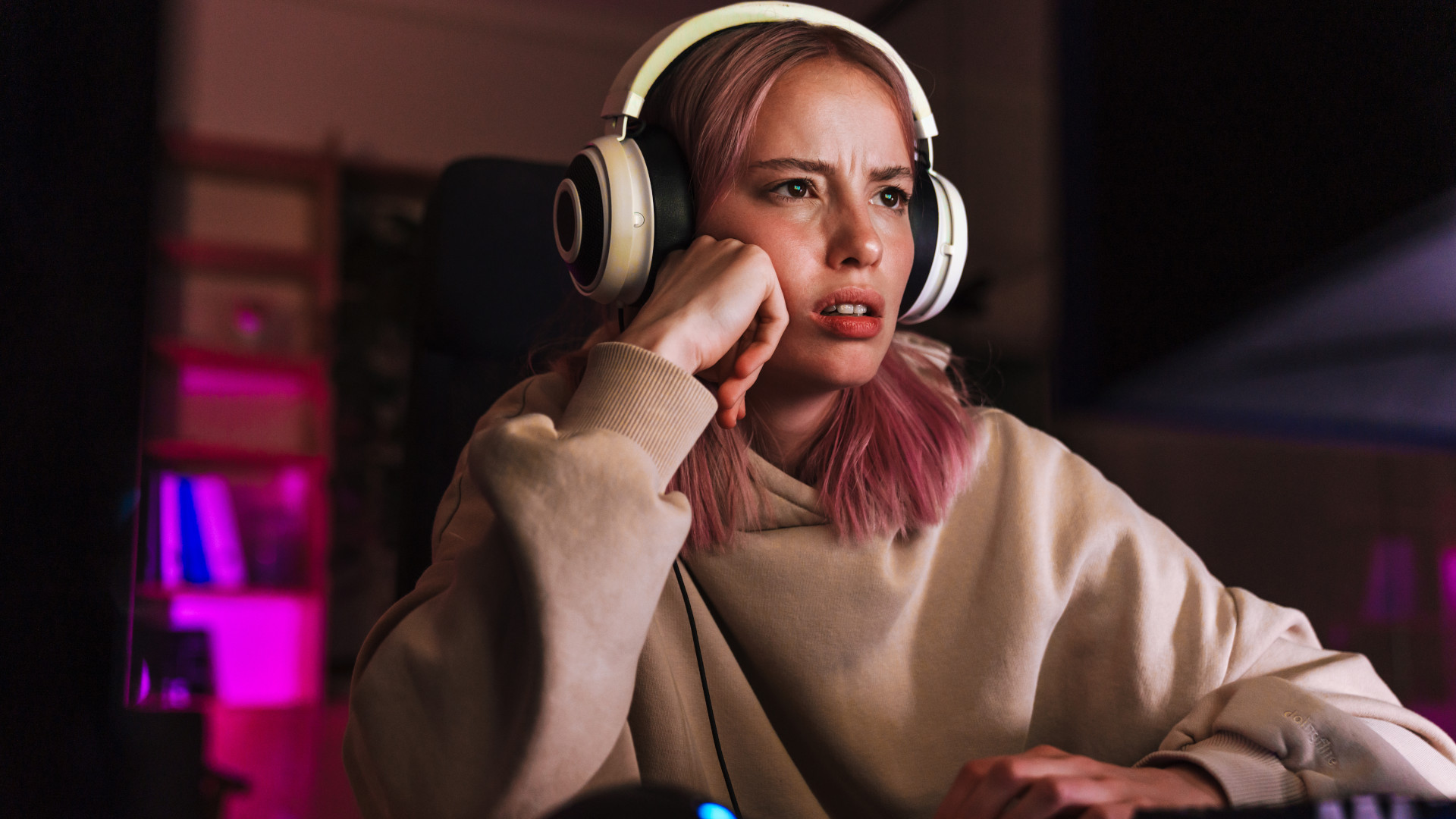 A frustrated looking girl sat in front of a gaming PC