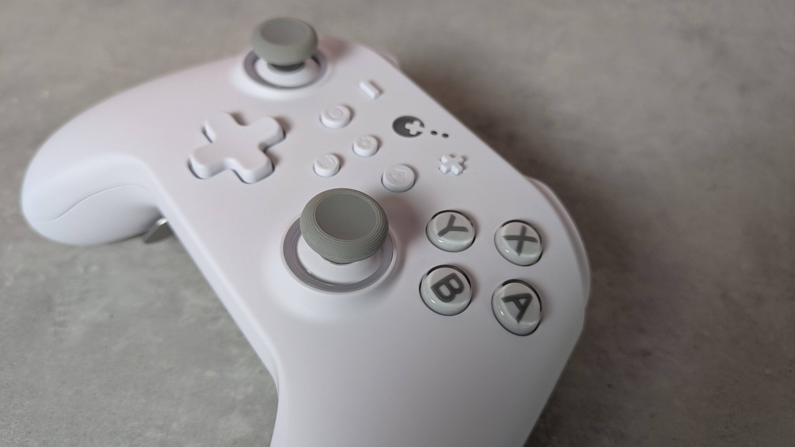 Close-up of right analog stick on GuliKit KK3 Max, on a grey desk