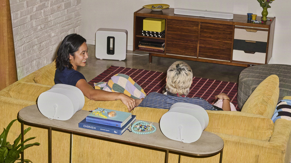 Two people sitting in a living room surrounded by Sonos products