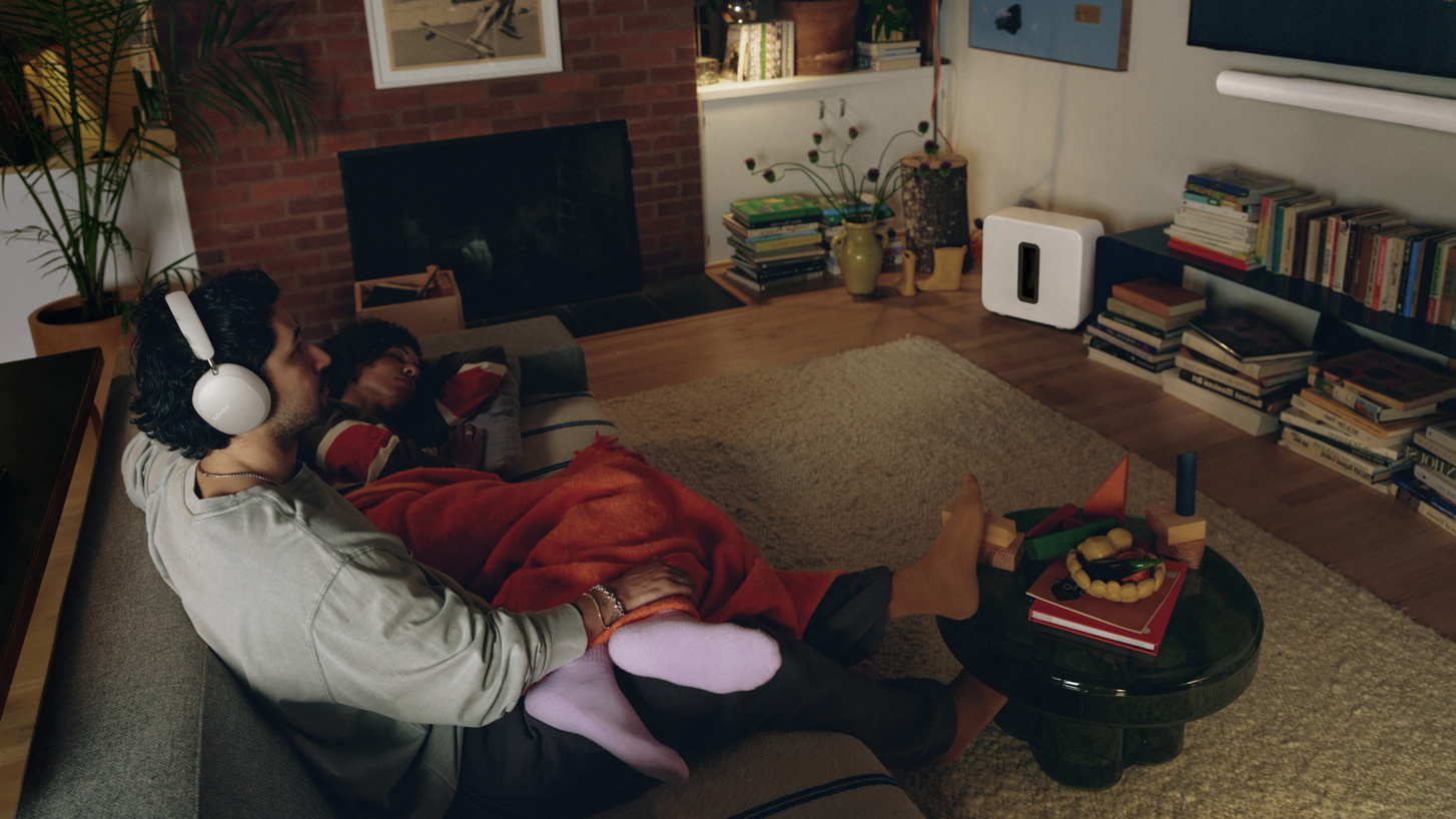 A person sitting in this living room listening to Sonos Ace Ultra headphones